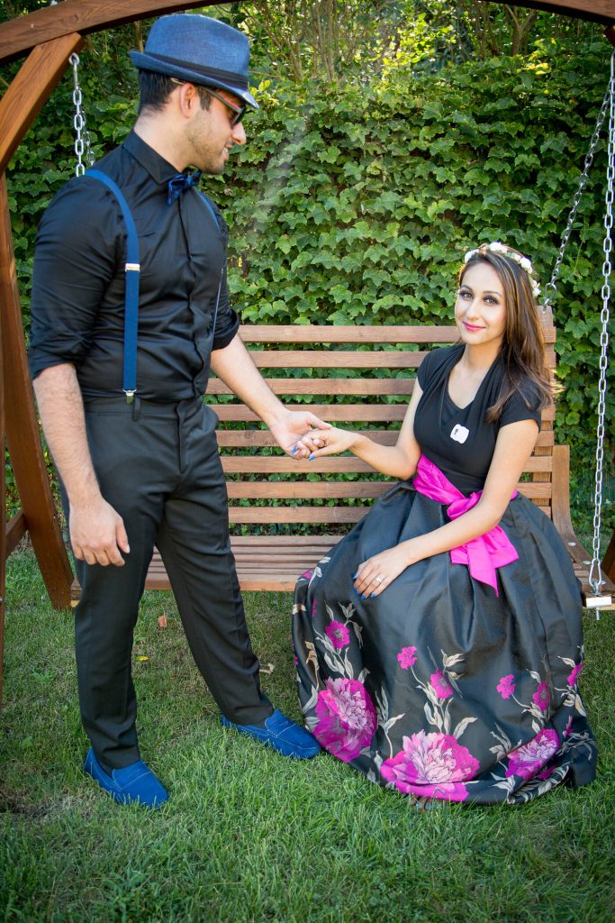 Indian husband and Indian wife holding hands on a yard swing for a baby shower