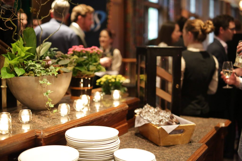 plates, candles and silverware with corporate people mingling in the background