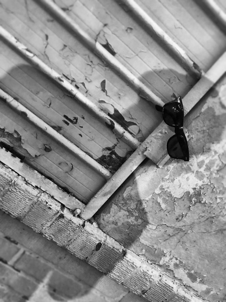 urban scene of peeling paint with a shadow wearing classic Ray Ban sunglasses